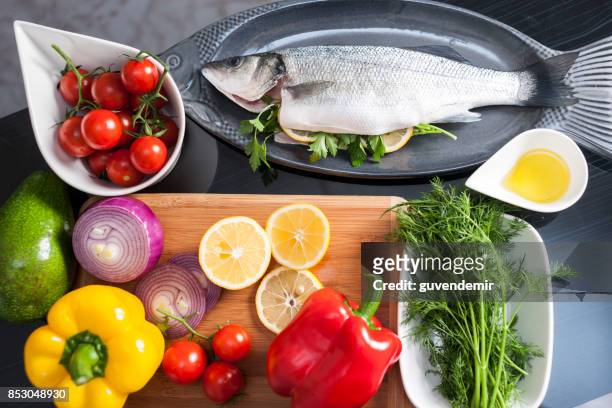 raw uncooked sea bass with  lemon, olive oil, herbs and spices - mediterranean sea stock pictures, royalty-free photos & images