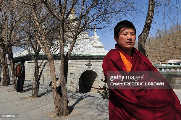 Tibetan Buddhist monk walks past a stupa at the Kumbum Monastery outside of Xining on March 8, 2009 in northwest China's Qinghai province, a vast...