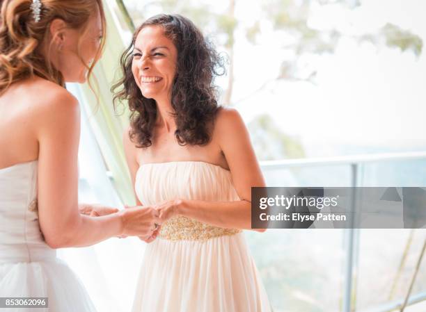 a bride grins with joy as her bride puts the wedding ring on her finger during their wedding in australia. - australia marriage stockfoto's en -beelden