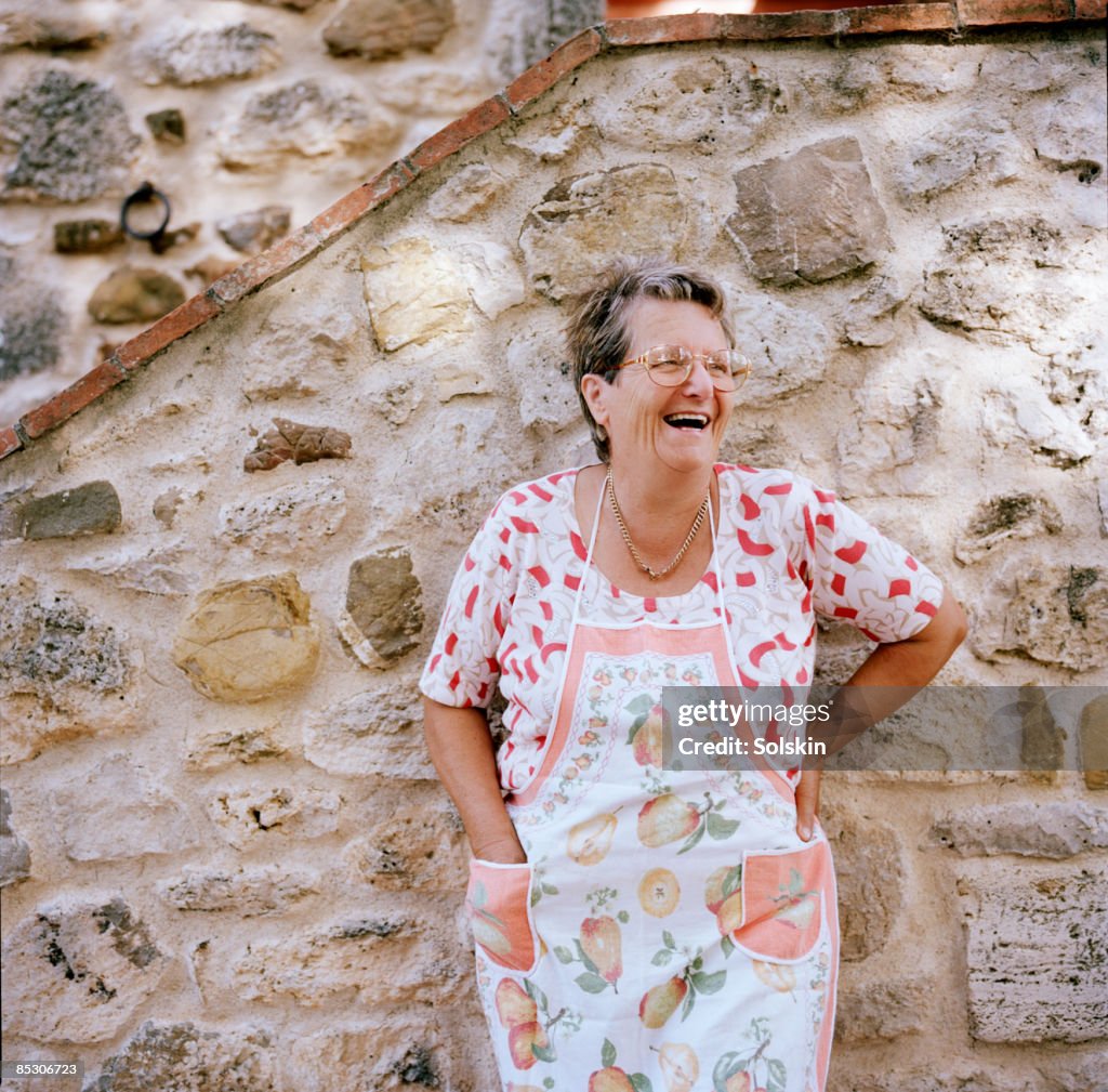 Mature woman standing outside house, smiling