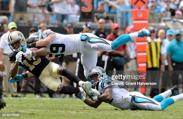 Michael Thomas of the New Orleans Saints makes a catch against Luke Kuechly and Captain Munnerlyn of the Carolina Panthers during their game at Bank...
