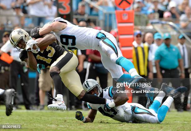 Michael Thomas of the New Orleans Saints makes a catch against Luke Kuechly and Captain Munnerlyn of the Carolina Panthers during their game at Bank...