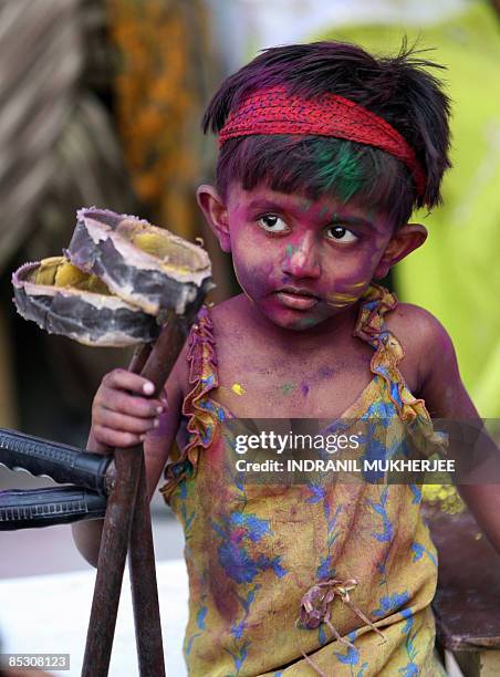 Physically handicapped Indian girl collects her crutches after being smeared with gulal-coloured powder at a special school- Society for the...