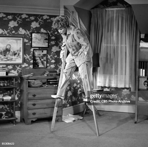 American actress and comedienne Lucille Ball , as Lucille Carmichael, walks on stilts while dressed in pyjamas on an episode of 'The Lucy Show'...