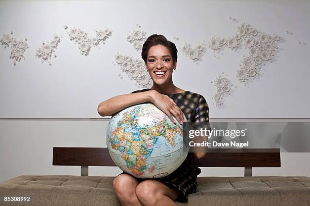 young woman smiling and holding a globe in her lap - holding globe imagens e fotografias de stock