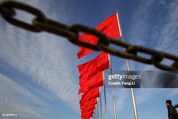 Photographer stands under the red flags at Beijing's Tiananmen Square during a plenary session of the annual National People's Congress in the...