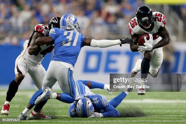 Tevin Coleman of the Atlanta Falcons runs over D.J. Hayden of the Detroit Lions and Jalen Reeves-Maybin during the second quarter at Ford Field on...