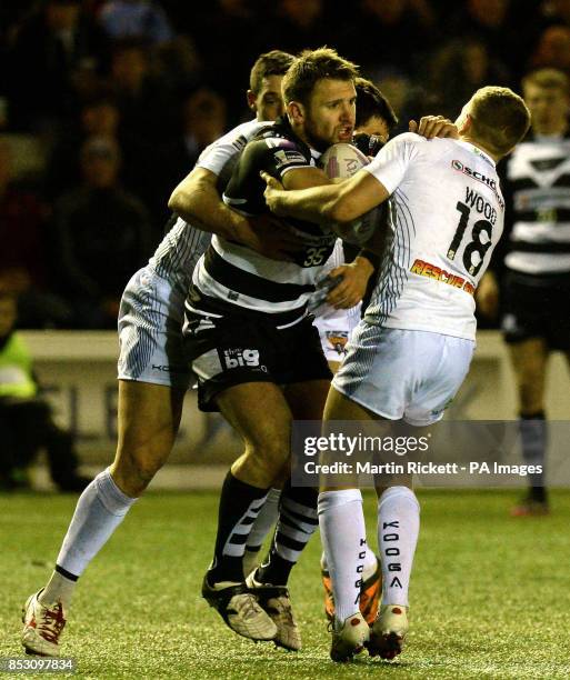 Widnes Vikings Paul Clough is tackled by Huddersfield Giants Brett Ferres and Kyle Wood, during the First Utility Super League match at the Select...