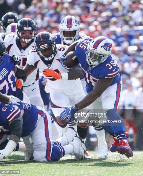 Mike Tolbert of the Buffalo Bills runs the ball as Todd Davis of the Denver Broncos attempts to tackle him during an NFL game on September 24, 2017...