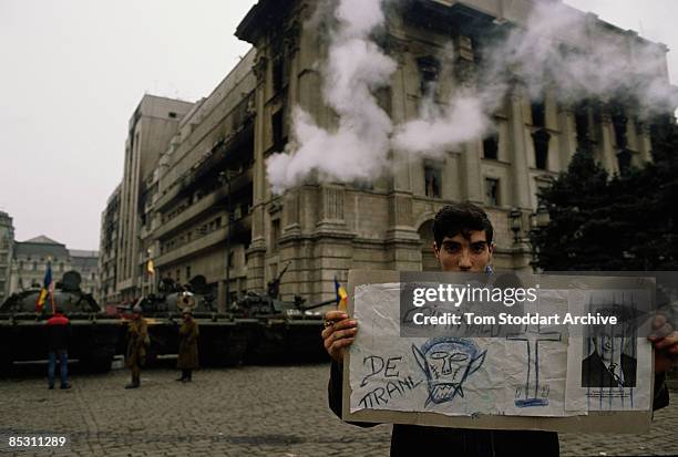 Young man holds up a hand-drawn poster denouncing Romanian president Nicolae Ceausescu in Palace Square, later renamed Revolution Square, Bucharest,...