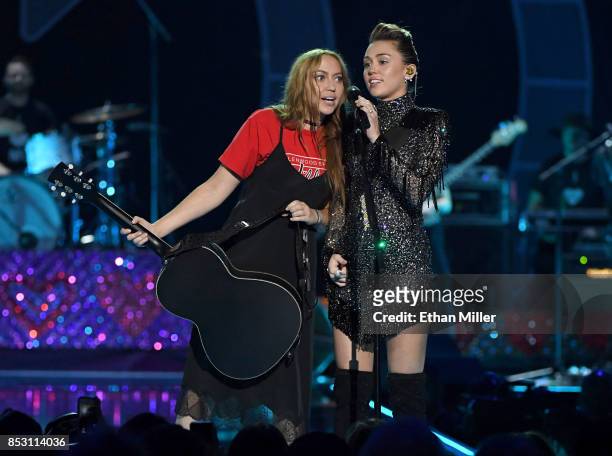 Brandi Cyrus gives her sister Miley Cyrus a guitar as she performs during the 2017 iHeartRadio Music Festival at T-Mobile Arena on September 23, 2017...