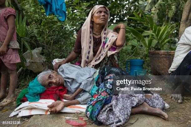 Bhelua Khatun, age 70, exhausted from his journey rests on the side of the road as his daughter Anwara ,45 looks for humanitarian aid after a new...