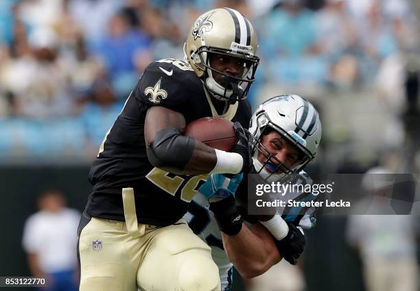 Adrian Peterson of the New Orleans Saints runs with the ball against Luke Kuechly of the Carolina Panthers during their game at Bank of America...