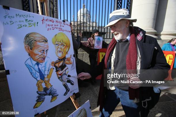 Caricature artist Ray Sherlock displays a drawing of German Chancellor Angela Merkel and Taoiseach Enda Kenny before they arrive for a press...