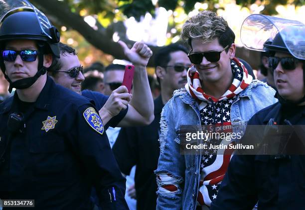 Right wing commentator Milo Yiannopoulos is escorted by police officers after he spoke during a free speech rally at U.C. Berkeley on September 24,...