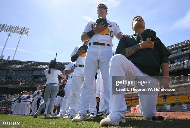 Bruce Maxwell of the Oakland Athletics kneels in protest next to teammate Mark Canha duing the singing of the National Anthem prior to the start of...