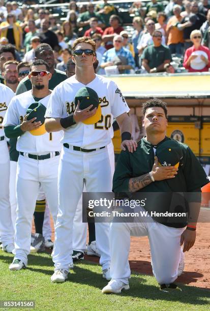 Bruce Maxwell of the Oakland Athletics kneels in protest next to teammate Mark Canha duing the singing of the National Anthem prior to the start of...