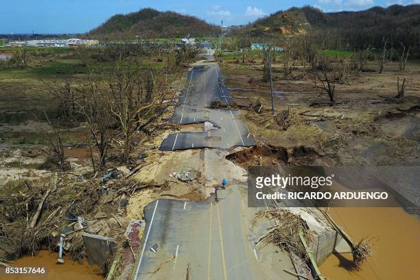 Man rides his bicycle through a damaged road in Toa Alta, west of San Juan, Puerto Rico, on September 24, 2017 following the passage of Hurricane...