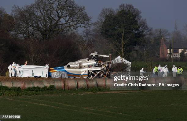 Forensic officers examine the wreckage of a helicopter alongside the A146 after four people died when the helicopter came down in thick fog in a...