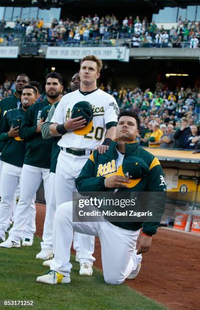 Mark Canha of the Oakland Athletics puts his hand on the should of Bruce Maxwell as Maxwell kneels during the anthem prior to the game against the...