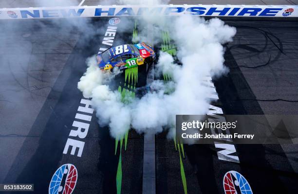 Kyle Busch, driver of the M&M's Caramel Toyota, celebrates with a burnout after winning the Monster Energy NASCAR Cup Series ISM Connect 300 at New...