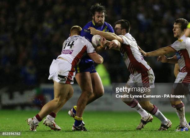 Warrington Wolves Trent Waterhouse is tackled by Wigan Warriors Jack Hughes, Darrell Goulding and Logan Tomkins during the First Utility Super League...