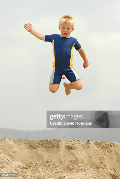 jumping boy on the beach - boy in swimwear stock-fotos und bilder