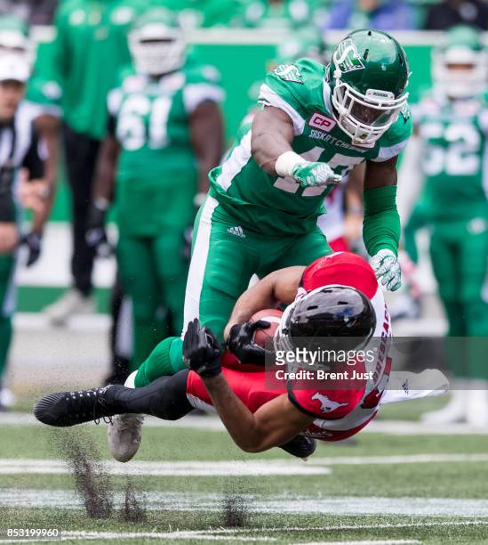 Juwan Brescacin of the Calgary Stampeders is levelled by Samuel Eguavoen of the Saskatchewan Roughriders in first half action of the game between the...