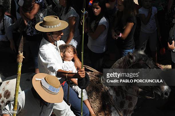 Gaucho holds his asleep daughter as he rides his horse during the Patria Gaucha festival on March 7 in Tacuarembo, Uruguay. During a week,...