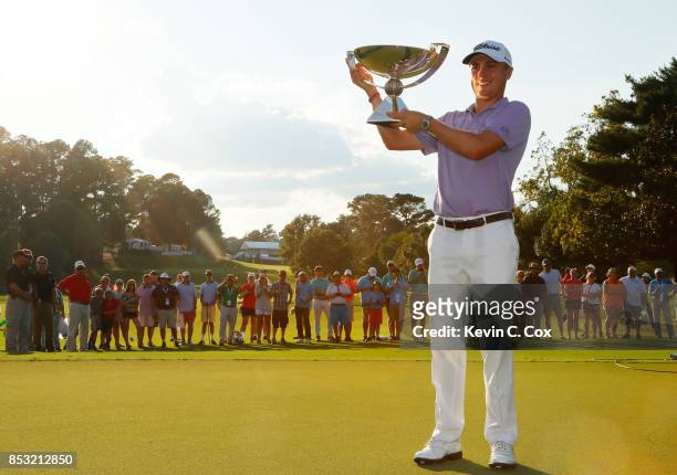 Justin Thomas of the United States celebrates with the trophy on the 18th green after winning the FedExCup and second in the TOUR Championship during...