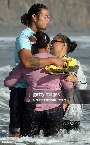 Family and friends are overcome with emotion as they walk into the water to release flowers after a memorial service for missing Warriors NRL player...