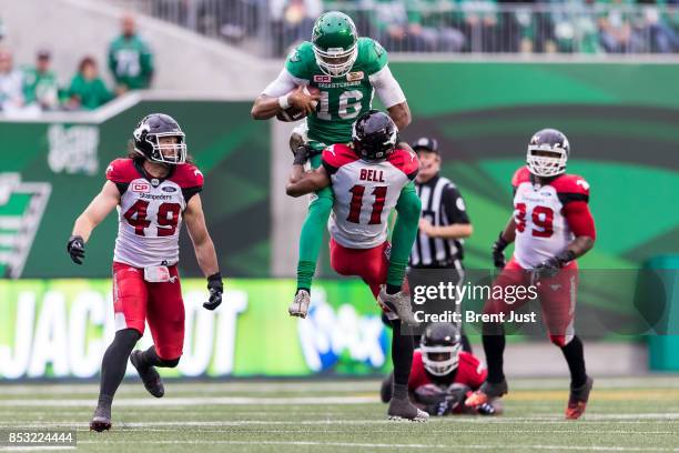 Brandon Bridge of the Saskatchewan Roughriders tries to hurdle Joshua Bell of the Calgary Stampeders after scrambling with the ball in the second...