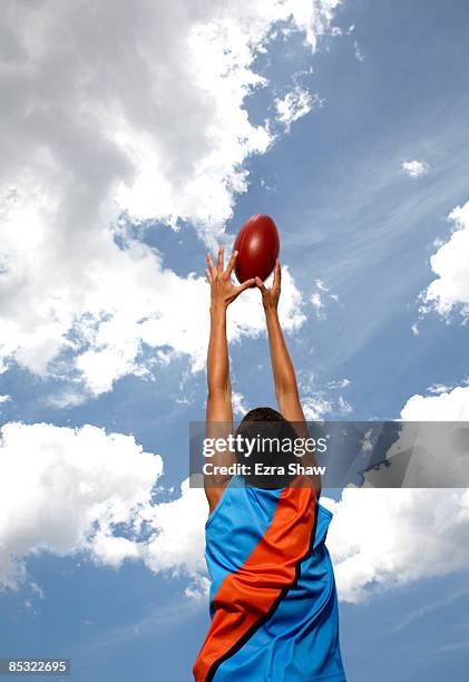 player jumping to catch australian football - australian rules football ball stock pictures, royalty-free photos & images