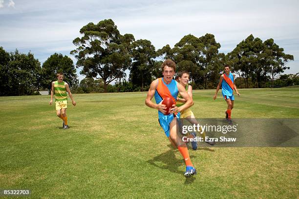 player running from opposition with football - afl footy stock pictures, royalty-free photos & images