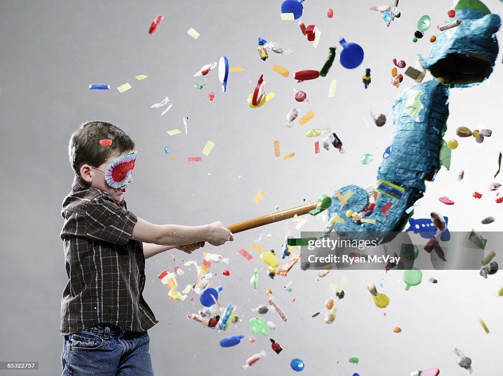 Boy hitting pinata, explosion of candy