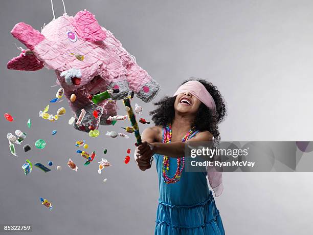 girl hitting pinata, candy flying - papier stock pictures, royalty-free photos & images