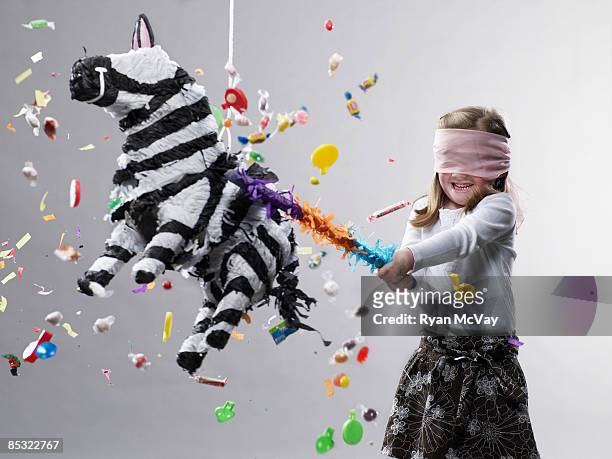 young girl hitting pinata, candy flying - schommelen bungelen stockfoto's en -beelden