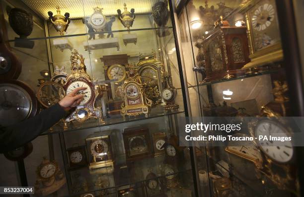 Nick Tarrant adjusts an 1850 bronze and gilt clock at the London Antique Clock Centre in Portobello Road, London, before the clocks go forward this...