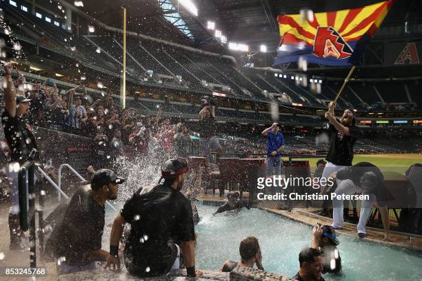 Pitcher Archie Bradley of the Arizona Diamondbacks waves an Arizona flag as the team celebrates in the outfield pool after defeating the Miami...