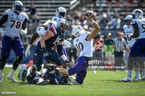 East Carolina quarterback Thomas Sirk is brought down for a loss by Connecticut's Junior Joseph in the first periodat Rentschler Field in East...