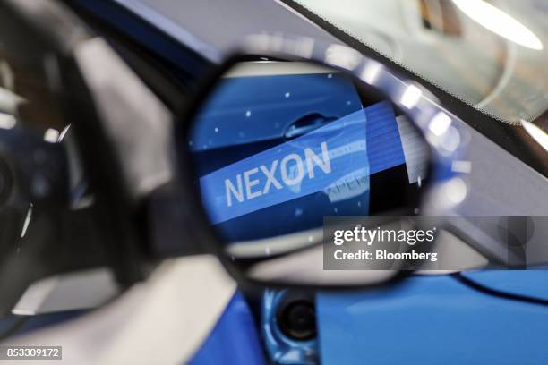 The logo of Tata Motors Ltd.'s new Nexon sports utility vehicle is reflected in the side view mirror of the SUV during a launch event in Mumbai,...