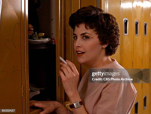 American actress Sherilyn Fenn smokes a cigarette at a locker in school hallway set in a scene screen grab from the pilot episode of the television...