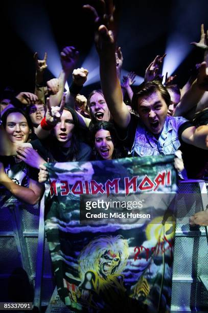 Photo of FANS and IRON MAIDEN, Iron Maiden fans in front row of sueicne at concert / gig - holding up poster, cheering, shouting