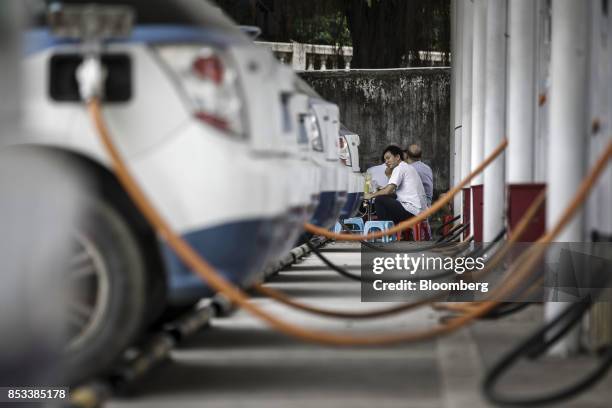 Charging cables sit connected a row of BYD Co. E6 electric taxis at the company's charging station in Shenzhen, China, on Wednesday, Sept. 20, 2017....