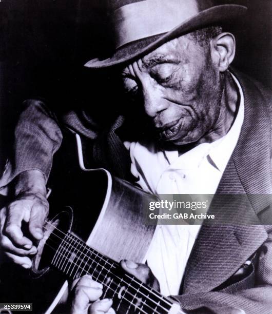 Photo of Mississippi John HURT; posed, playing guitar