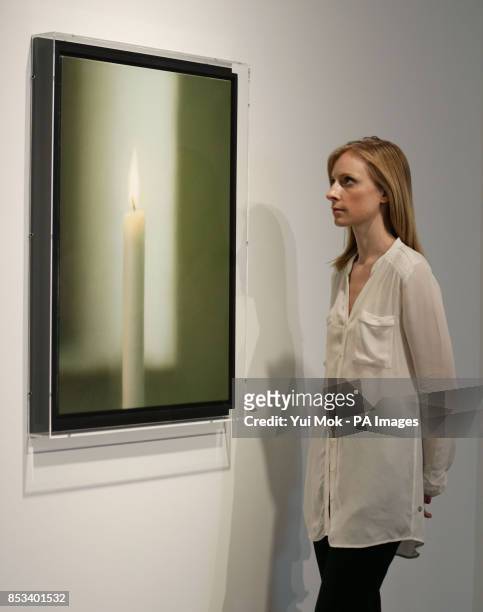 Christie's employee looking at a painting by Gerhard Richter, Kerze during a press view of the Polke/Richter-Richter/Polke exhibition - celebrating...