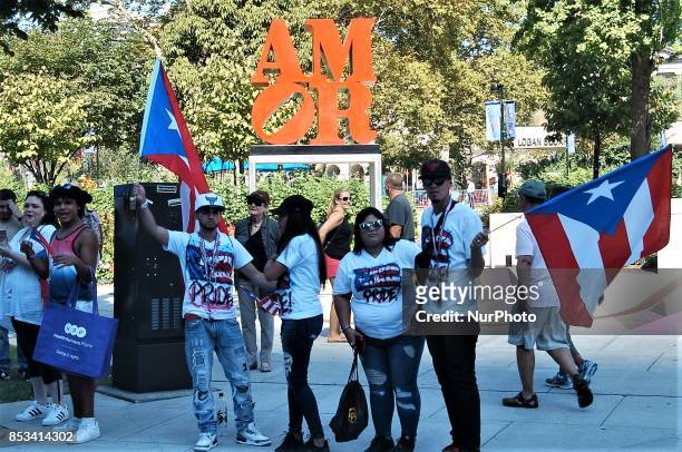 Group of revelers wave Puerto Rican flags and wear Puerto Rican pride shirts in form of the recently installed Amore art installation in downtown...