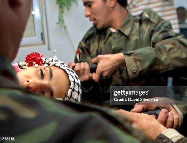 Uniformed Palestinian activists carry the body of Hussam al-Disi into his family home during his funeral February 27, 2001 in the West Bank town of...