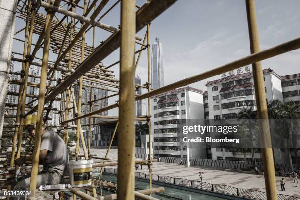 Worker sits on a scaffolding at a construction site as the Ping An International Finance Center stands in the background in Shenzhen, China, on...