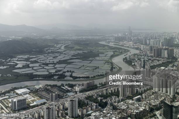 The Sham Chun river marking the border between residential and commercial buildings in mainland China, right, and farmland in Hong Kong is seen from...